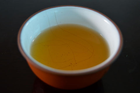 Cup of green Gunpowder Pearls tea by Lake Missoula Tea Company, showcasing tightly rolled green tea pearls in a clear cup.