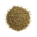 Fresh brewed Lake Missoula Tea Company peppermint tea in a clear glass cup with mint leaves on a wooden table.
