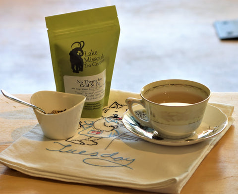 Cup of No Thyme for Cold & Flu herbal tea by Lake Missoula Tea Company in a glass mug with fresh thyme sprigs.