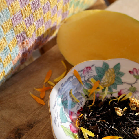 Fresh marigold tea blend by Lake Missoula Tea Company, Mango Love Not War, displayed in a cozy fabric setting.