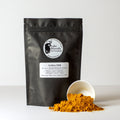 Golden Milk tea from Lake Missoula Tea Company in a clear glass cup with a warm, golden hue and a sprinkle of turmeric on top.