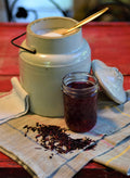 Dried hibiscus tea leaves from Lake Missoula Tea Company in a clear glass jar, showcasing vibrant red hibiscus flowers.