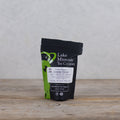A 2oz package of Lake Missoula Tea Company's jasmine green tea with fresh green leaves and jasmine blossoms.