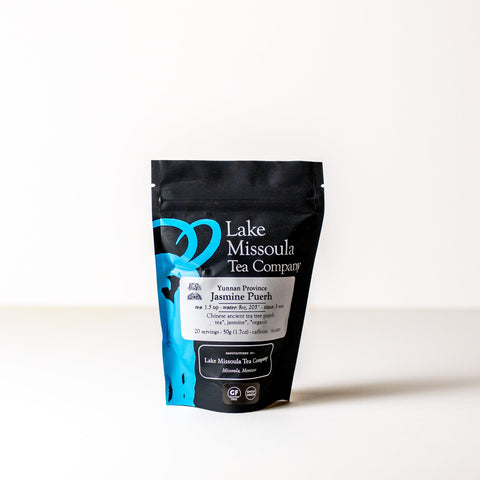 Dried jasmine-puerh tea leaves from Lake Missoula Tea Company in a 2 oz package, showcasing fragrant, rolled tea leaves.