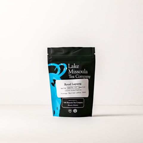 Two ounces of Lake Missoula Tea Company's Royal Lapsang tea in a clear glass jar with a black lid and a tea label.