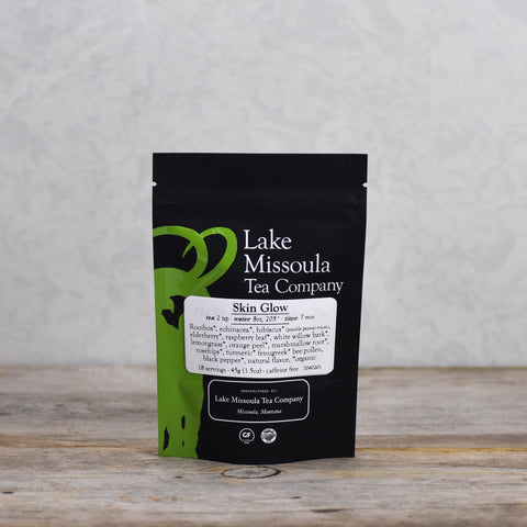 Two ounces of Lake Missoula Tea Company's Skin Glow herbal tea with dried herbs and flowers in a clear jar.