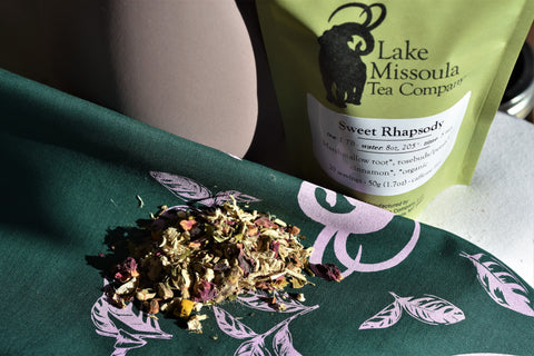 Loose leaf Sweet Rhapsody tea from Lake Missoula Tea Company displayed on a bandana. Bright, aromatic tea leaves in natural setting.