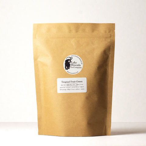 Green tea with tropical fruit flavor from Lake Missoula Tea Company, showing fresh green tea leaves and colorful tropical fruit pieces.