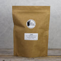 Lake Missoula Tea Company Uplift tea in 500g package, showing the colorful tea blend in a clear container with fresh herbs and flowers.