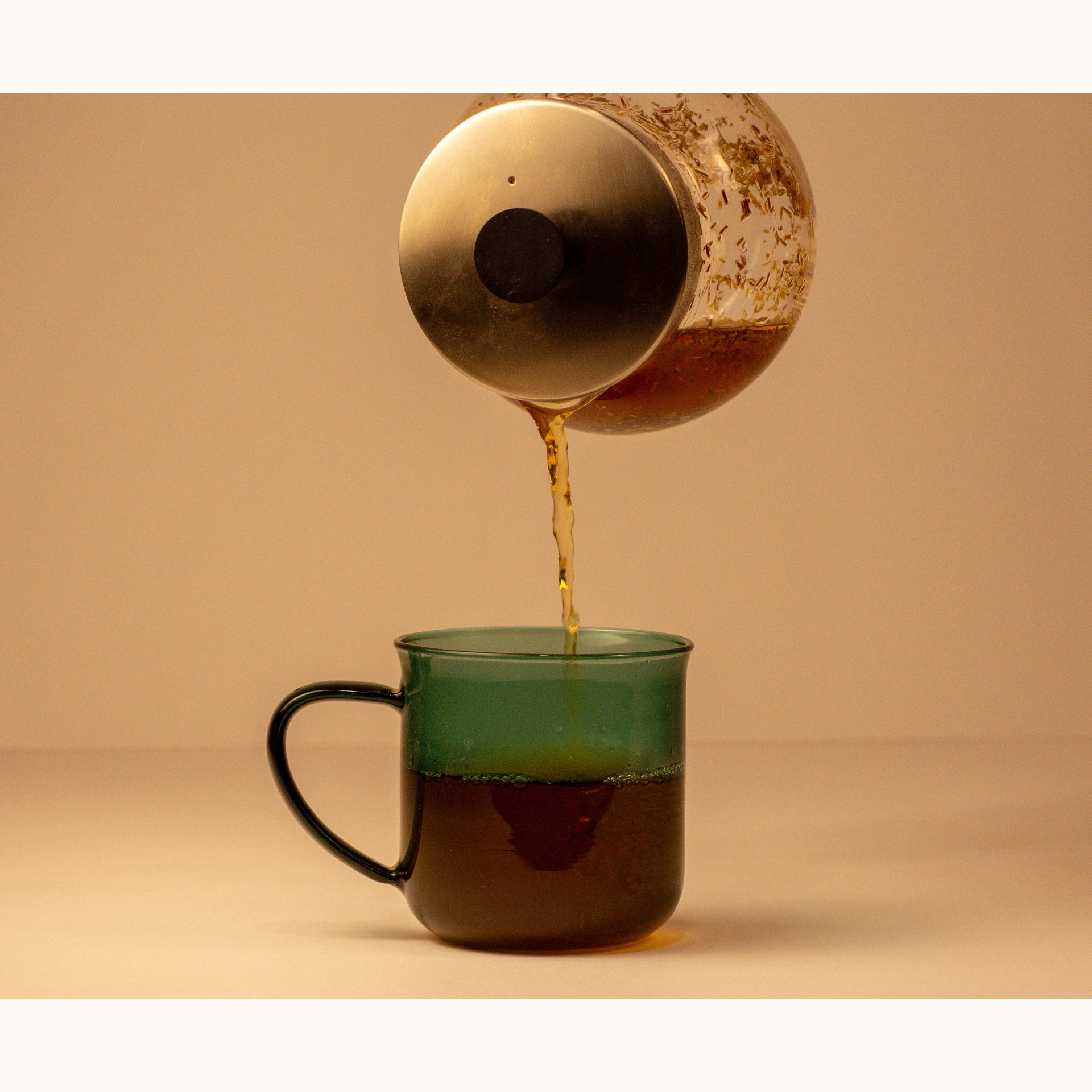 Green Rooibos pouring into glass tea mug